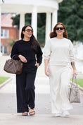 Load image into Gallery viewer, Two women walking outdoors on a paved path in front of a white domed pavilion. The woman on the left wears a black long-sleeve top and wide-leg pants with a brown patterned handbag.
